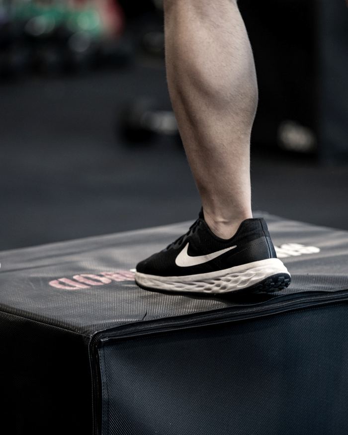 Detalle de una zapatilla sobre un cajón de salto con el logo de Singular WOD